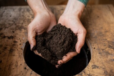 Someone presenting a handful of dark soil