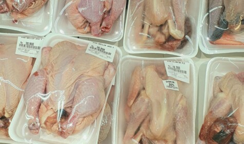 Multiple packages of chicken in a supermarket display case