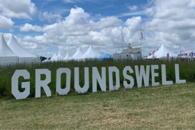A sign for Groundswell sits on the grass at the site with tents displayed in the background