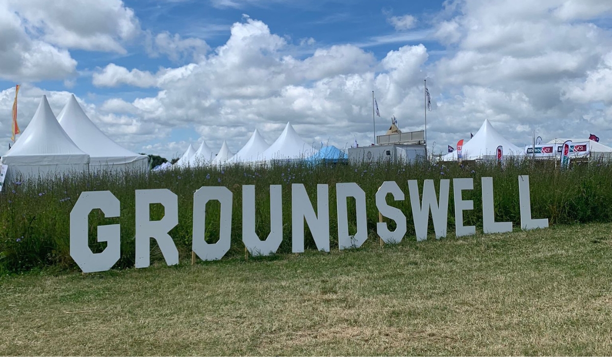 A sign for Groundswell sits on the grass at the site with tents displayed in the background