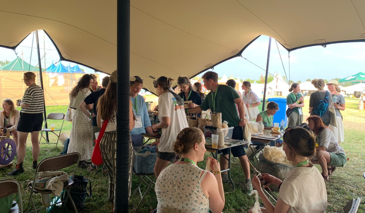 A couple of dozen people sit under a gazebo experimenting with wool and other animal by-product materials